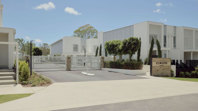 Gated entry to Elwood by Azure in Mango Hill with the Elwood sign and white rendered townhouses behind