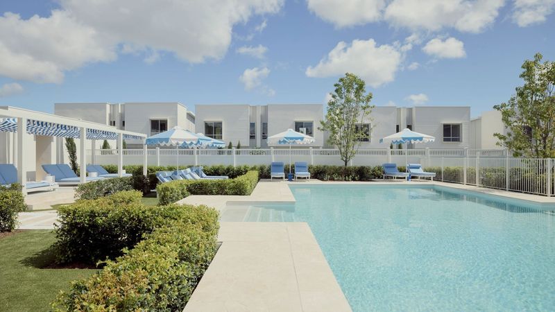 Pool and sun lounges at Elwood by Azure in Mango Hill, with a row of white rendered townhouses behind