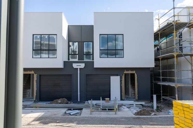 Ember by Azure townhouses under construction in Augustine Heights, white rendered upper levels with scaffold alongside
