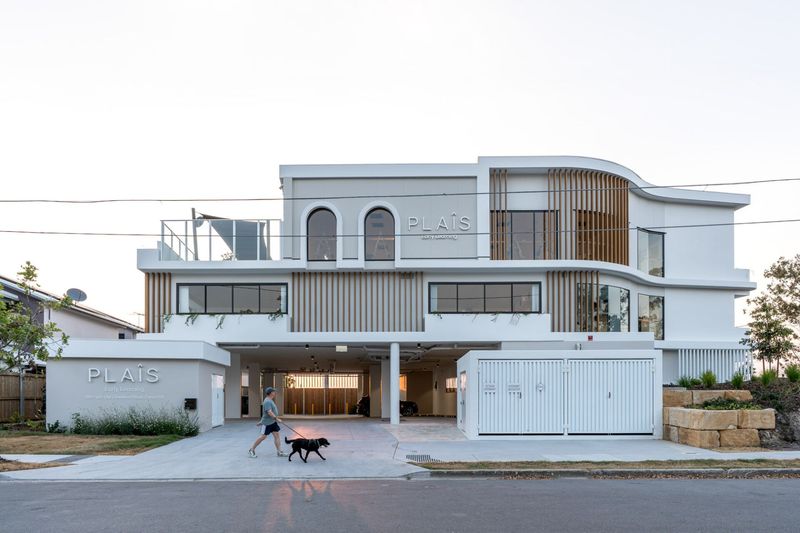 Plaîs Early Learning in Camp Hill, a three-storey childcare centre with curved white rendered walls, arched windows and timber battens