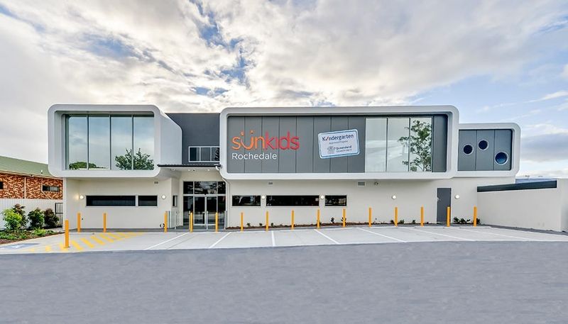 Sunkids Rochedale childcare centre, a two-storey building with white rendered walls and grey cladding above a car park
